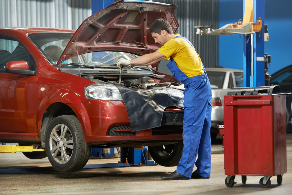 auto mechanic tighten screw with spanner during automobile car maintenance