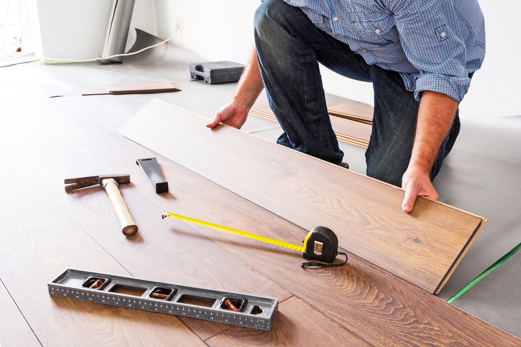 A person holding a piece of flooring with scattered tools