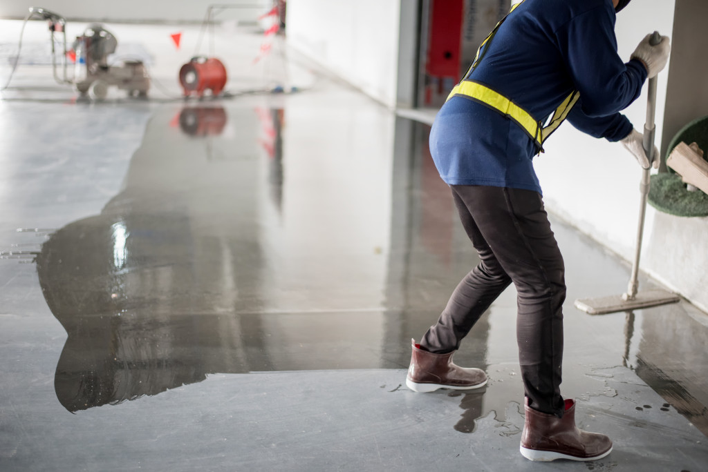 A worker spreading epoxy on the floor of a large room