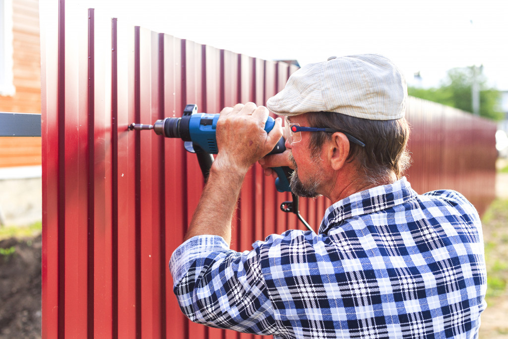 A handyman building a metal fence