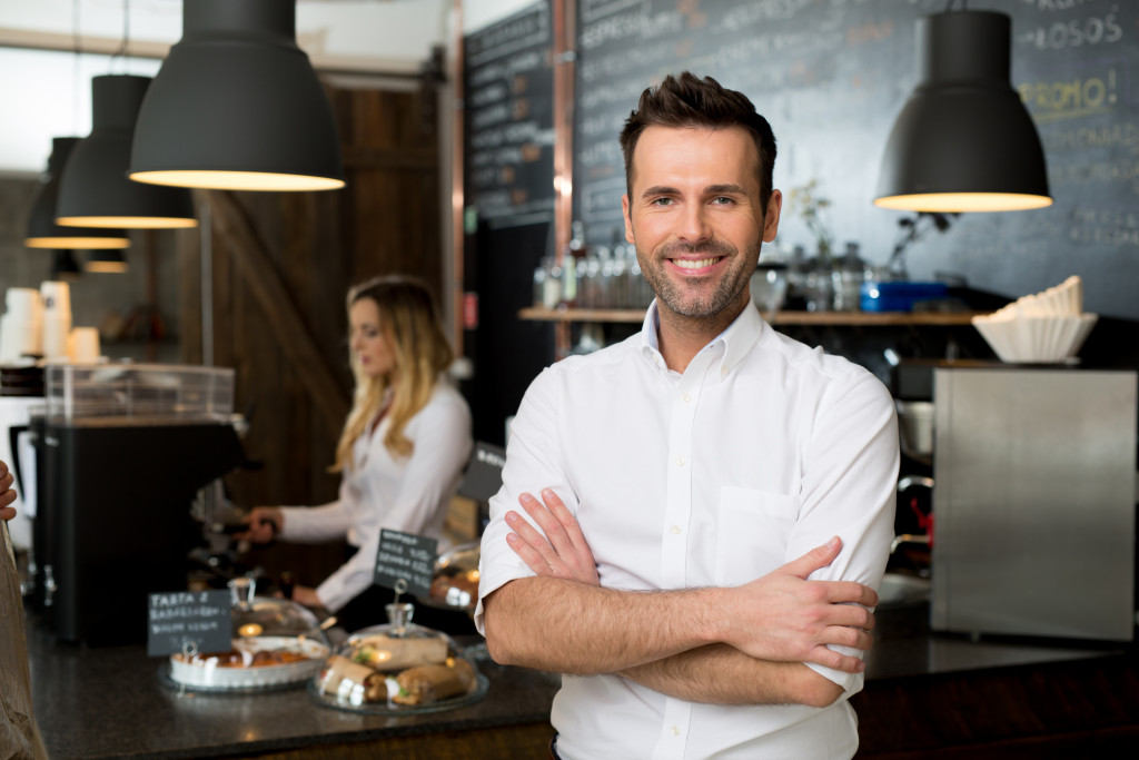 Successful small cafe owner standing with crossed arms