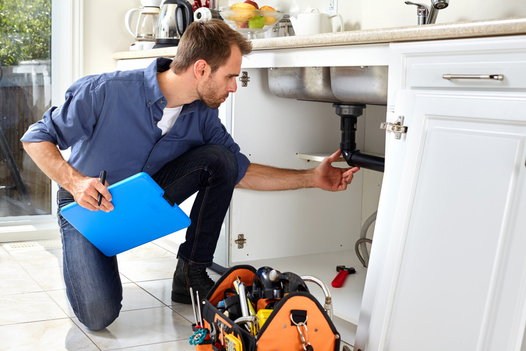 A plumber checking the pipes under a kitchen sink