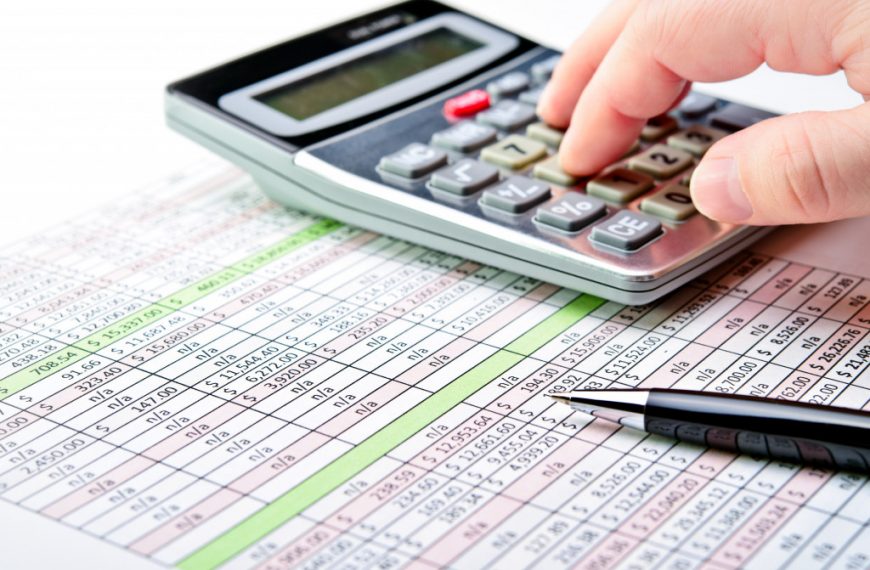 a person using a calculator and finance sheet to calculate tax