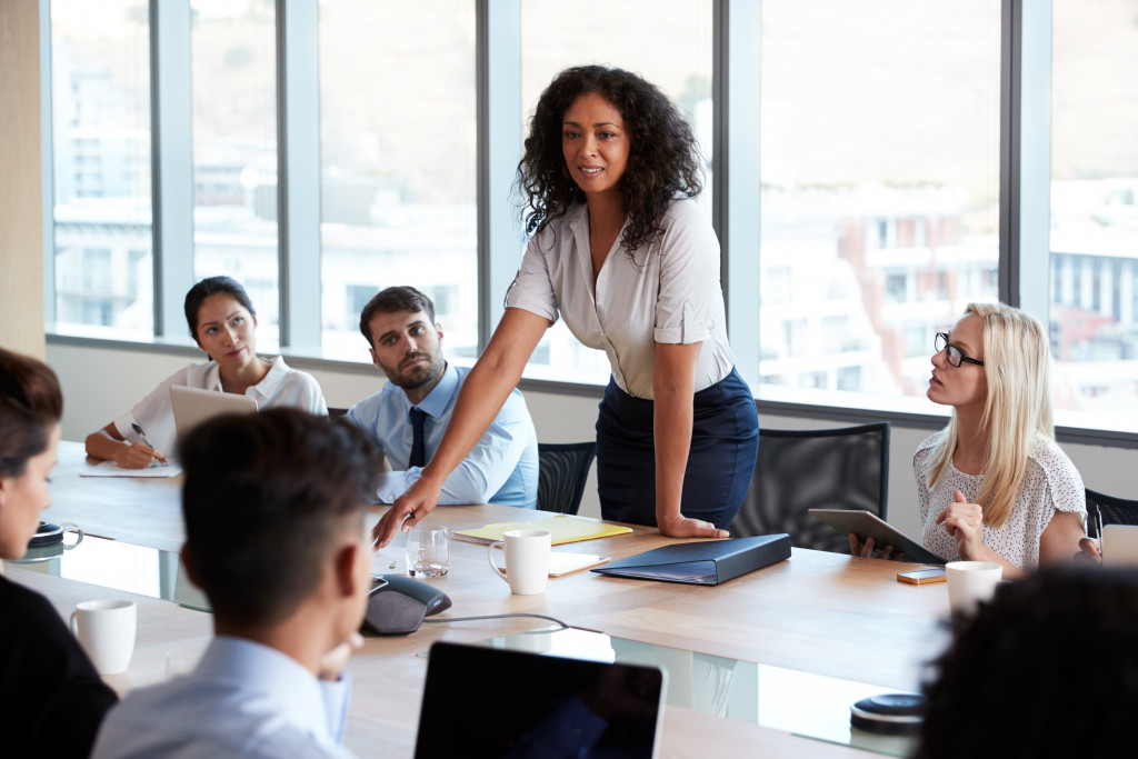 A businesswoman standing and speaking as her colleagues listen to her words