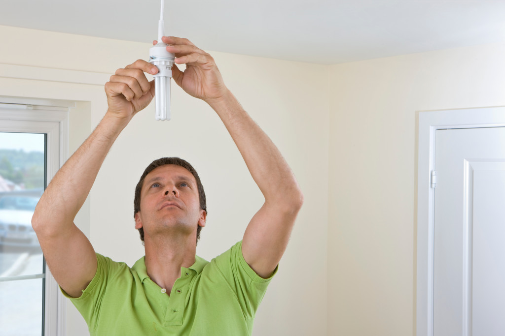 An electrician using a screwdriver for fitting the energy saving lightbulb