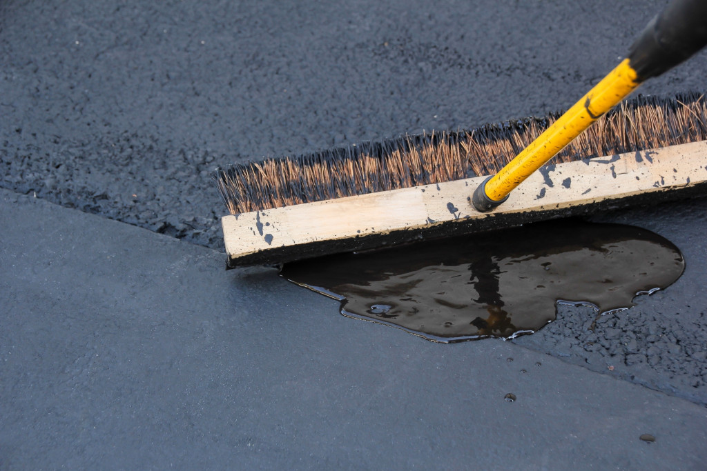 a man brushing asphalt sealing for the driveway