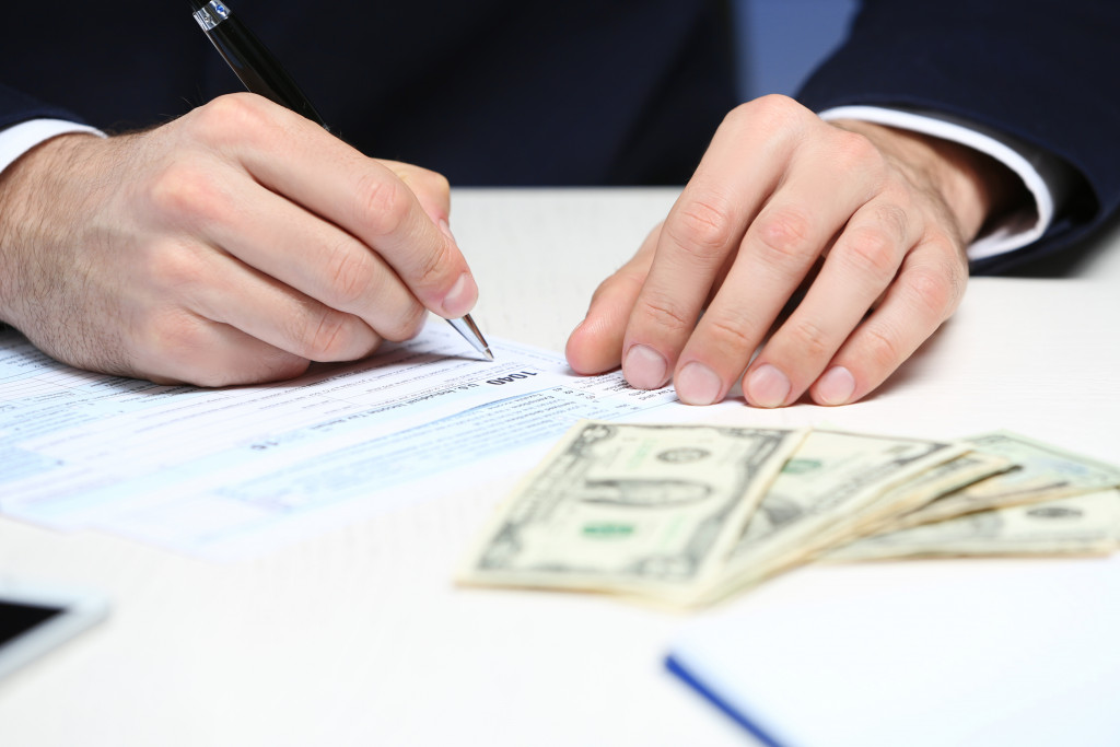 a professional signing a document with cash in the foreground