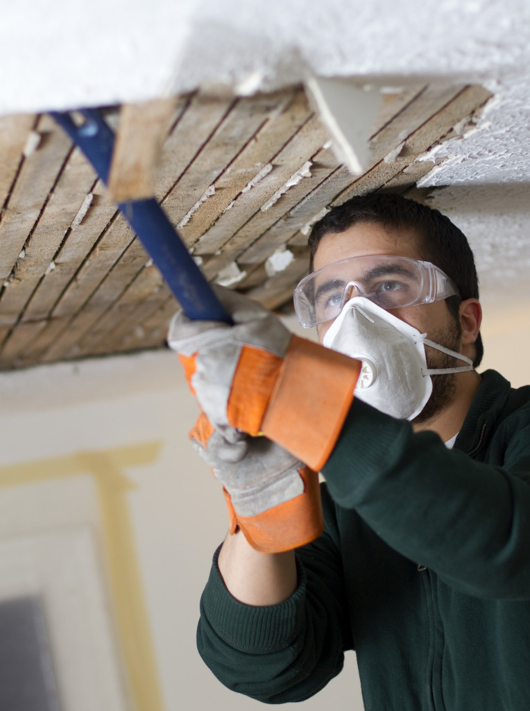 Worker removing the ceiling of a house.