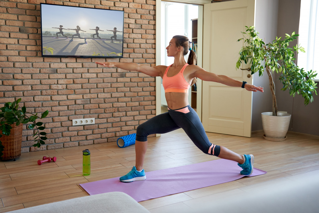 a woman at a fitness lounge following exercises on a TV