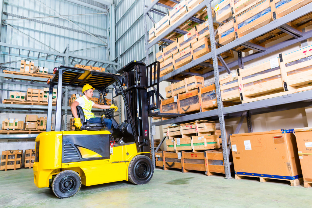 a man using a fork lift to sort packages in a warehouse