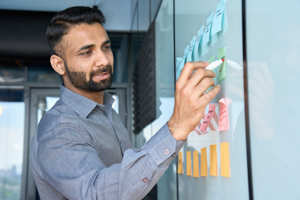 business man writing goals on sticky notes 