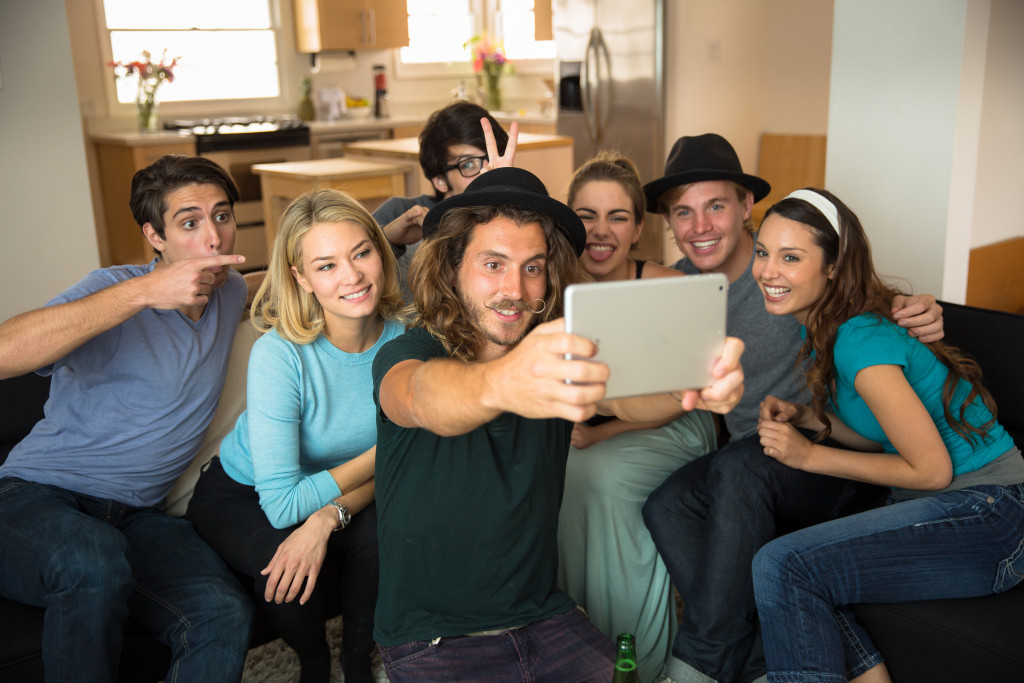 Group of millennials taking a selfie in a living room using a tablet.