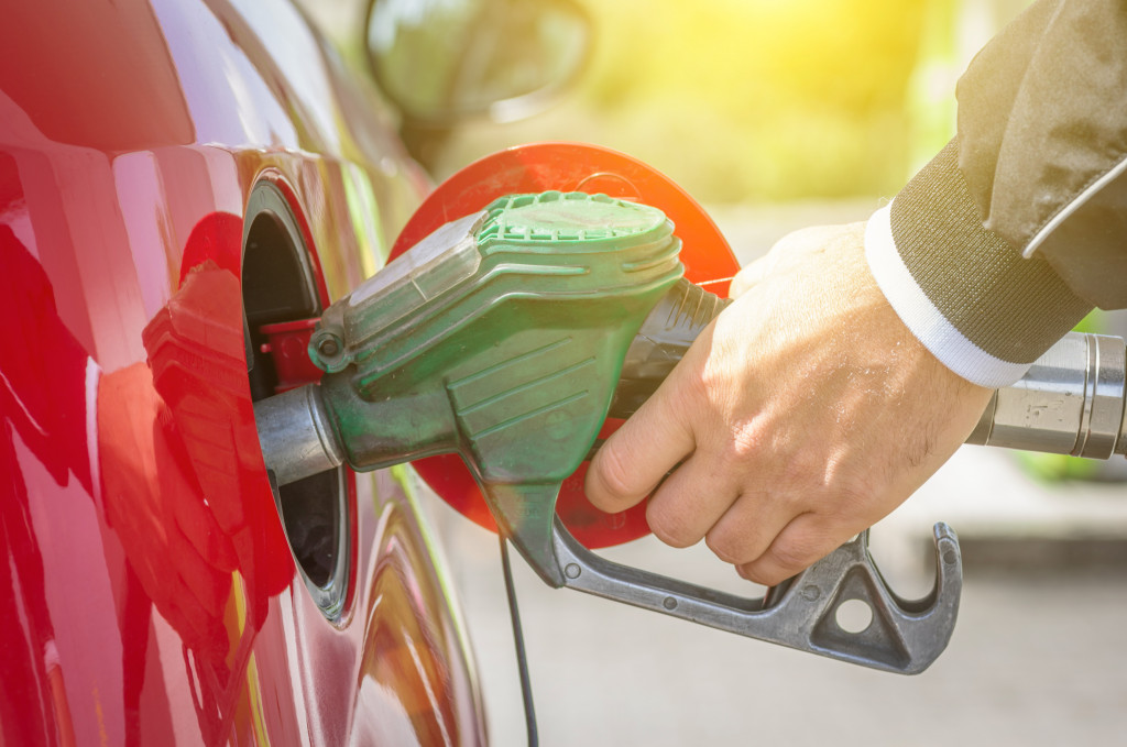 A hand refilling a car fuel tank