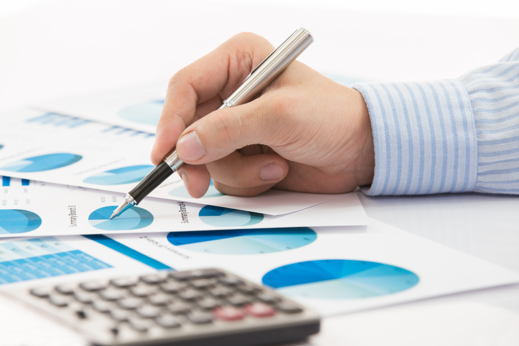 man with a pen and graphs spread on table