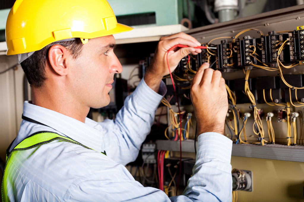 man in a hard hat tinkering electrical wirings