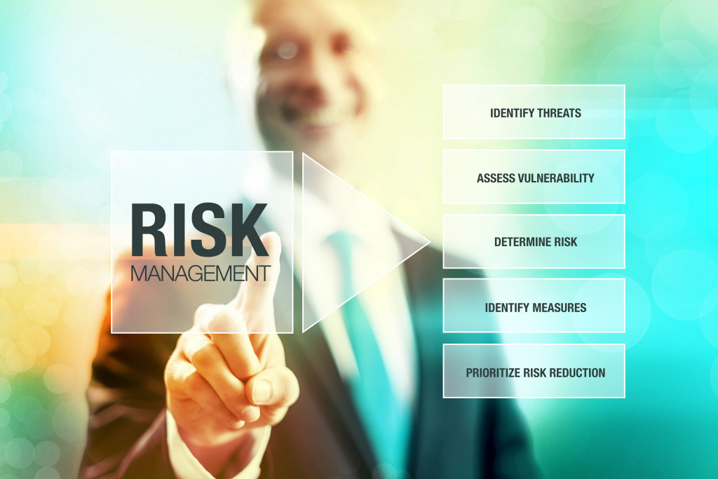 businessman smiling while touching risk management icon in the hologram