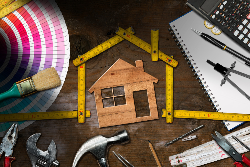 home maintenance represented by wooden house with tools around it