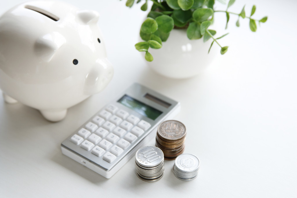 A white piggy bank with coins and a calculator