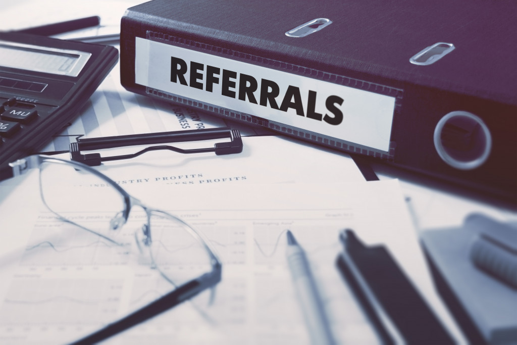 referrals in a black folder with papers on the table