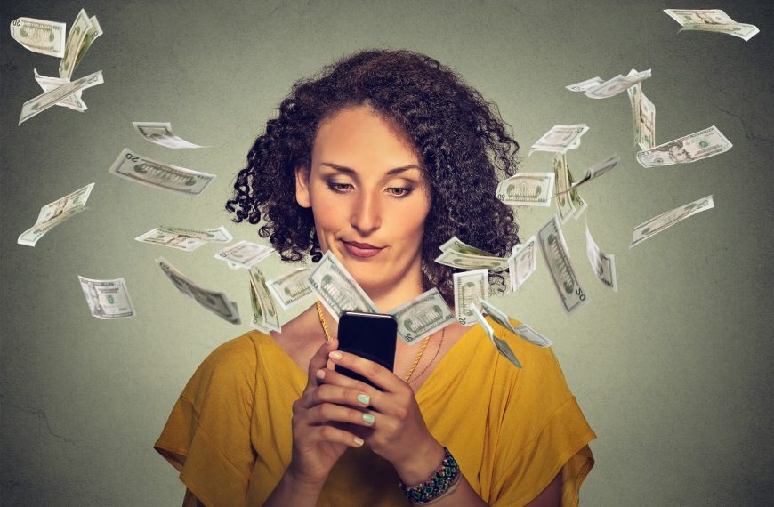 A woman using her phone while paper bills fly out of it